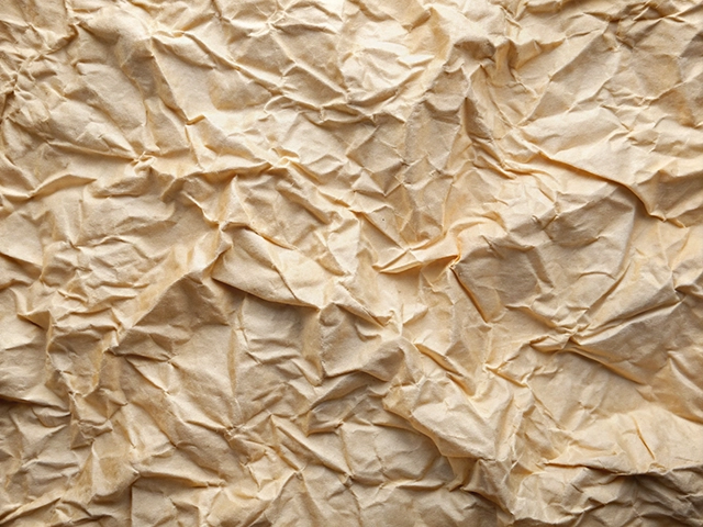 A close-up view of crumpled beige paper, showcasing its wrinkled surface and natural texture.