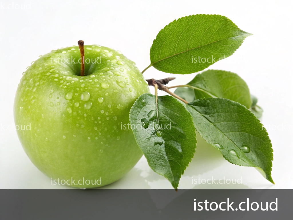 A fresh green apple with droplets of water on its surface, resting beside a branch with vibrant green leaves. The apple is placed on a clean white background, highlighting its freshness and dew.