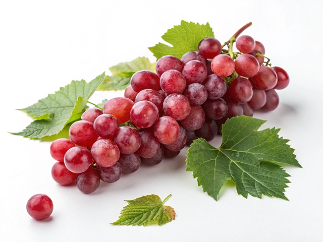 A bunch of ripe, red grapes with a few green leaves on a white background. One grape is separated from the bunch, lying next to the leaves.