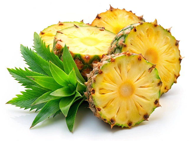 A cluster of sliced pineapple pieces is arranged on a white background, showcasing their vibrant yellow flesh and green outer skin, accompanied by fresh green leaves.