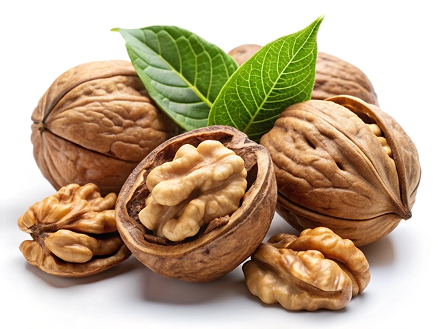 A collection of walnuts, some whole and some broken open to reveal the edible nut inside, accompanied by green leaves on a white background.